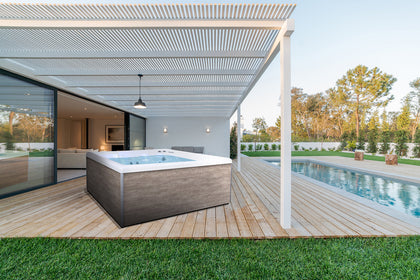 Spa NetSpa Square Wave 2 en terraza de madera bajo pérgola, junto a la piscina